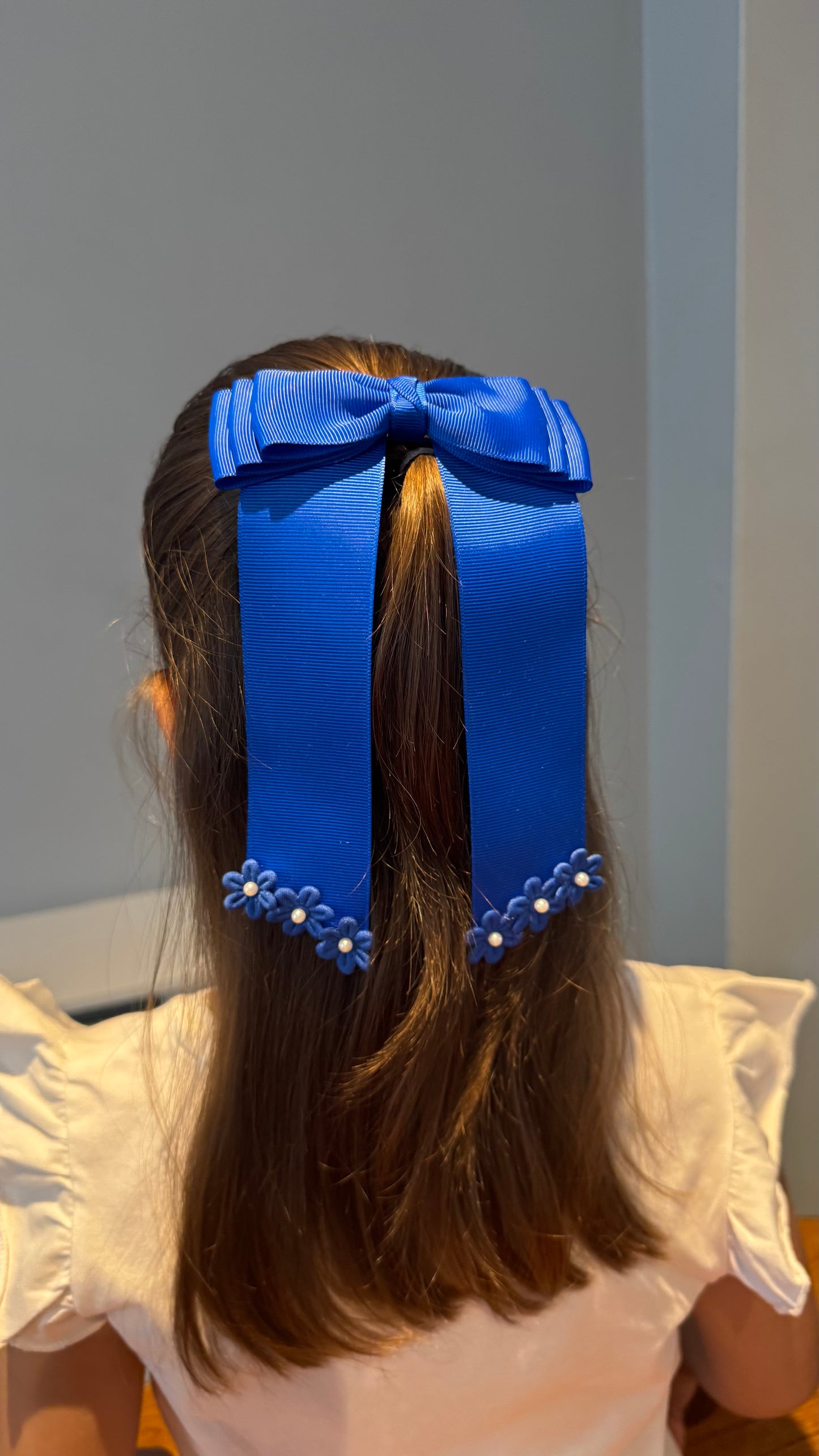 Green grosgrain long-tail bow with floral trim.