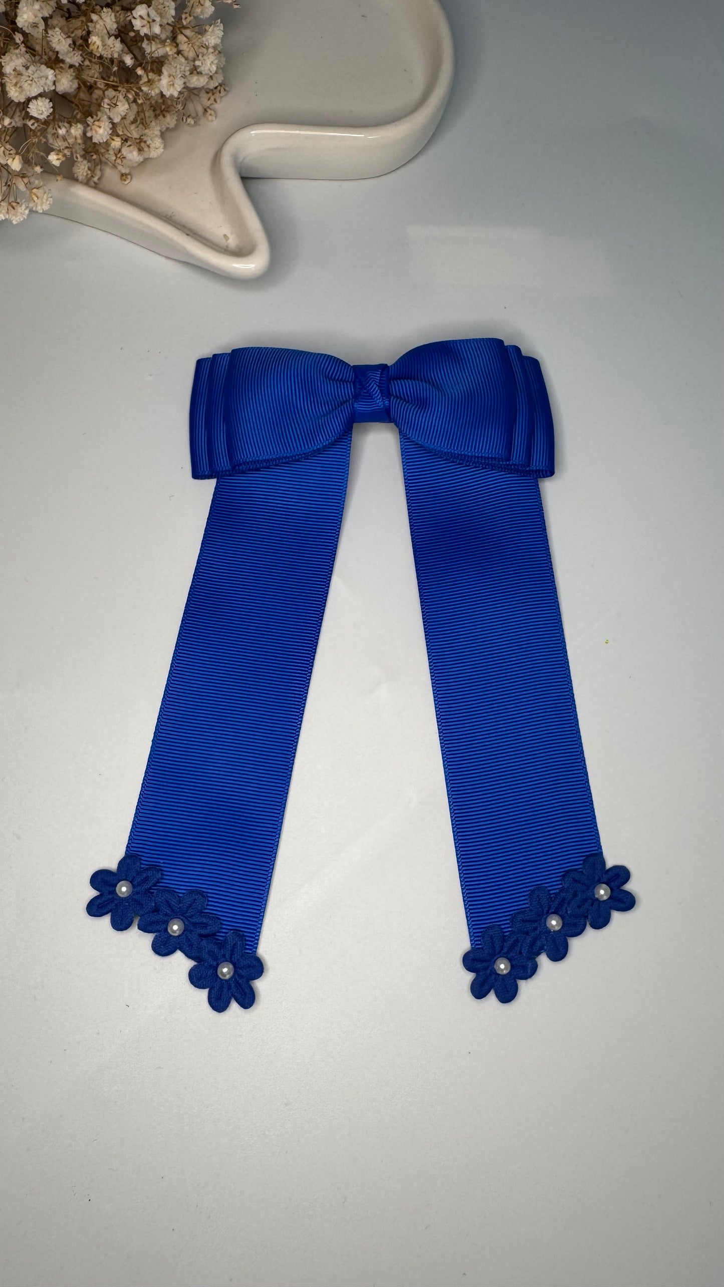 Green grosgrain long-tail bow with floral trim.