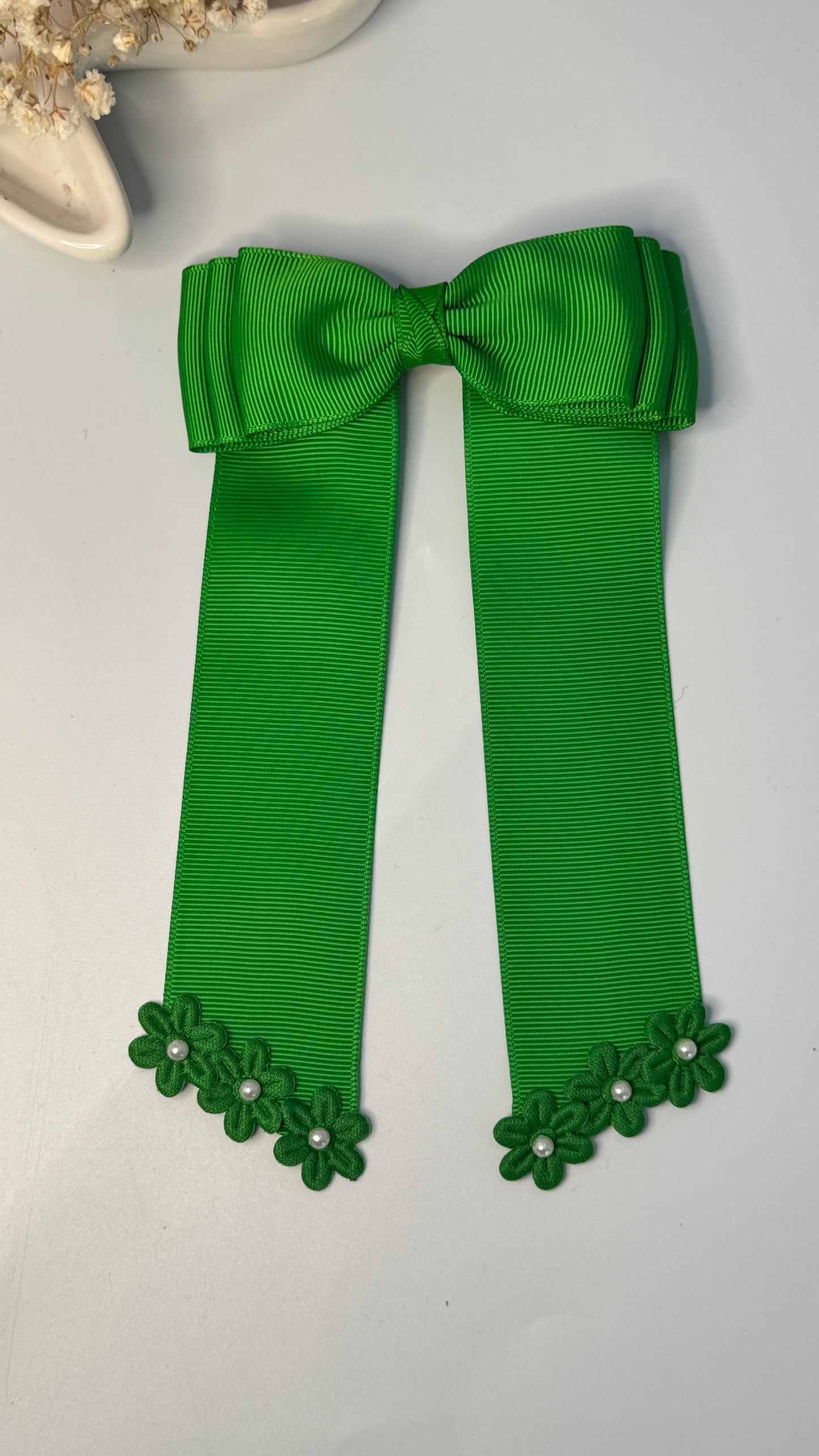 Green grosgrain long-tail bow with floral trim.