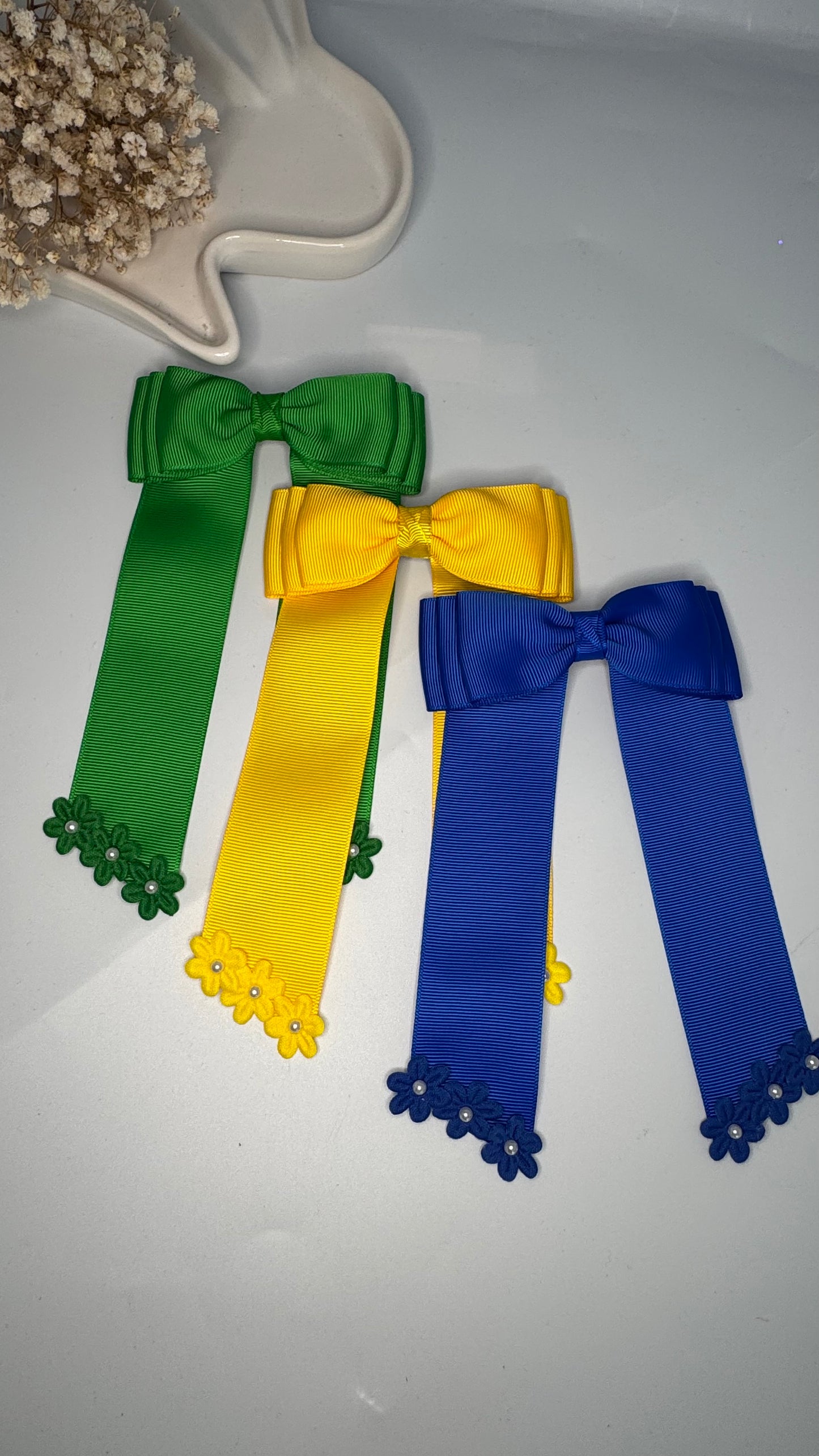 Green grosgrain long-tail bow with floral trim.