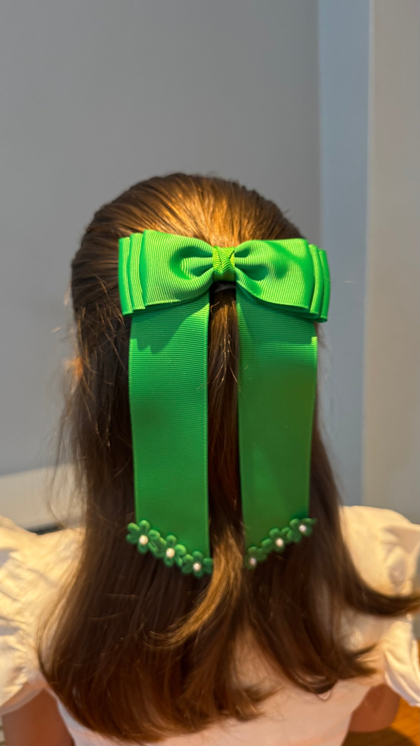 Green grosgrain long-tail bow with floral trim.