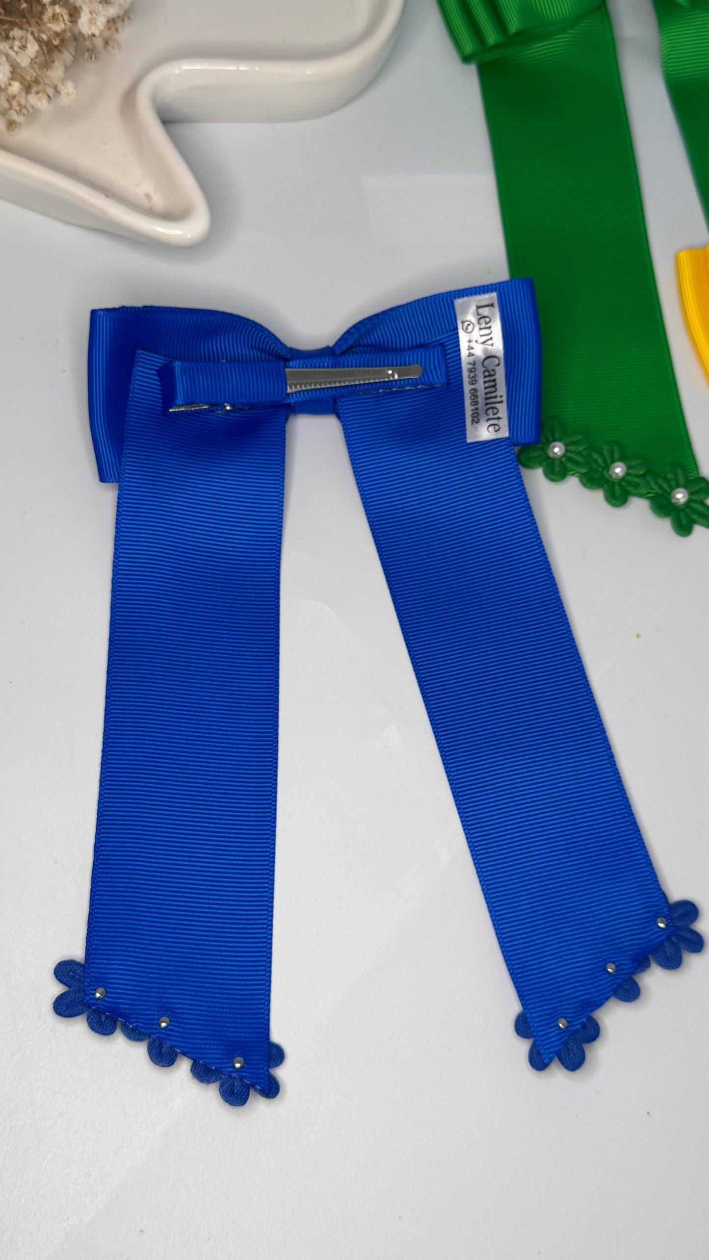 Green grosgrain long-tail bow with floral trim.