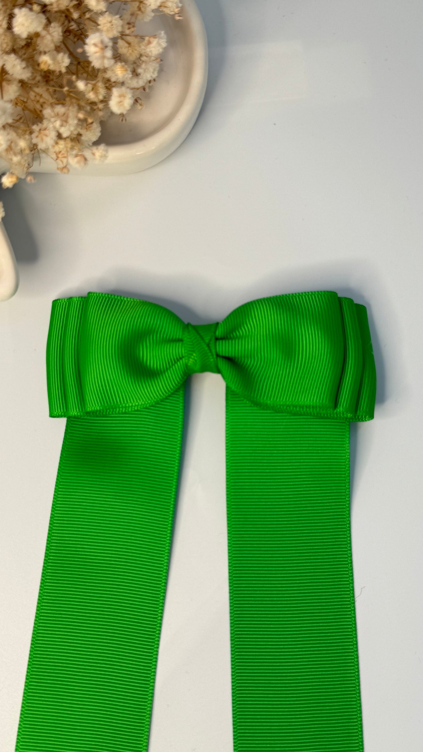 Green grosgrain long-tail bow with floral trim.