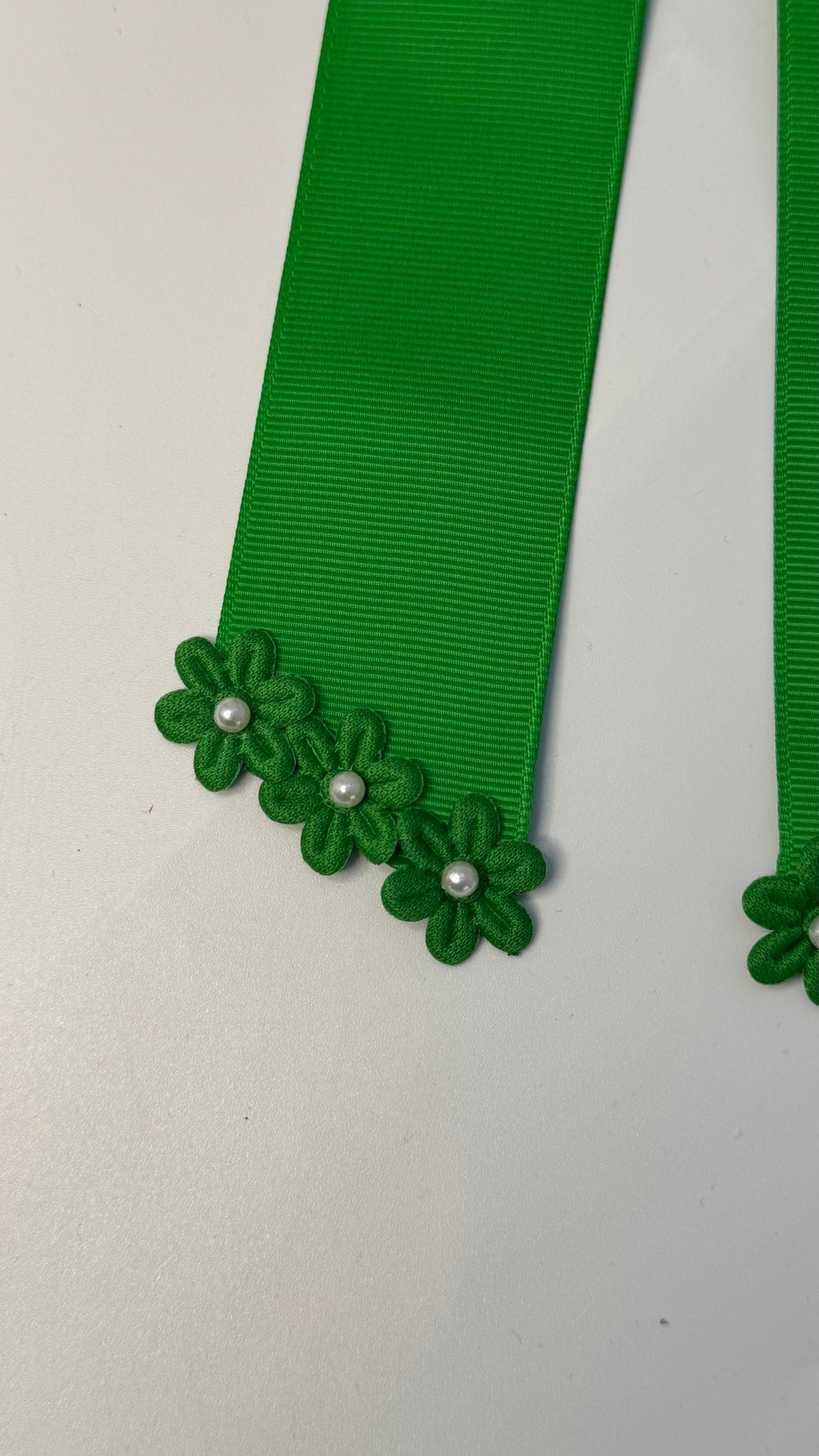 Green grosgrain long-tail bow with floral trim.